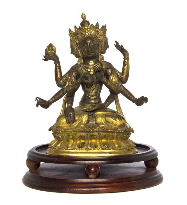 A Nepalese Gilt Bronze Figure of a Multi-Armed Dei: A Nepalese Gilt Bronze Figure of a Multi-Armed Deity, the three-headed figure having four pairs of arms with one hand holding a seated model of Buddha, raised upon a double lotus-form base. Height 7 i