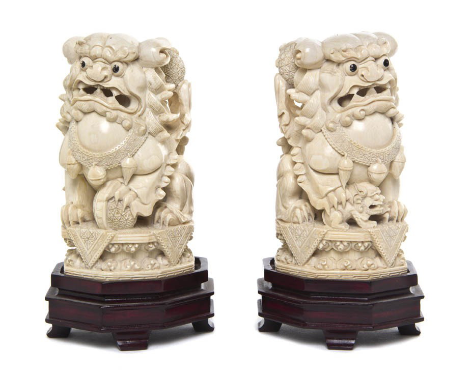 A Pair of Carved Ivory Fu Lions, Height 5 1/2 inch: A Pair of Carved Ivory Fu Lions, the lions depicted with puzzle balls and pups above octagonal bases, raised on conforming hardwood stands. Height 5 1/2 inches.