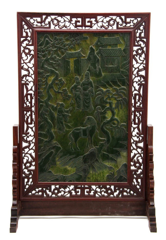 A Chinese Spinach Jade Table Screen, Height 23 1/2: A Chinese Spinach Jade Table Screen, carved in relief with scenes of a warrior with his attendant outside a city gate and walking toward his horse tied to a craggy tree, the stone tablet having inscri
