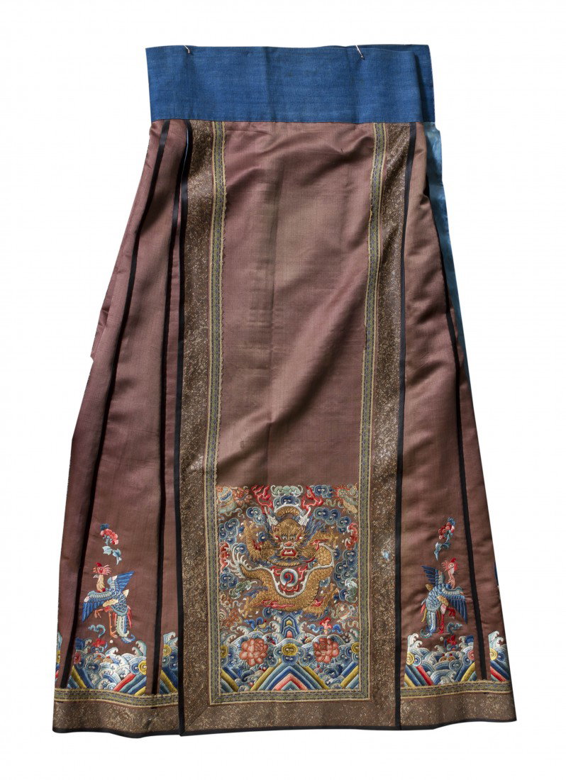 A Chinese Embroidered Skirt, Length approximately : A Chinese Embroidered Skirt, having embroidered decoration of a five-claw dragon surrounded by scrolling clouds and Buddhist emblems above crashing waves with a reserve of brown color. Length approxim