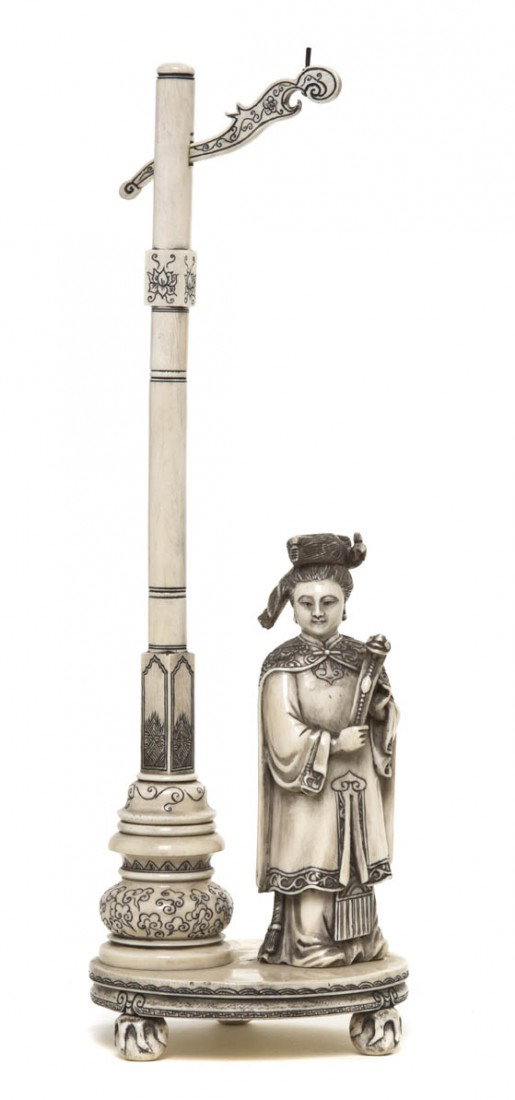 An Ivory Carving of a Lady, Height 14 inches.: An Ivory Carving of a Lady, the figure depicted with an embroidered cape and phoenix form hair ornament, holding a ruyi scepter and standing beneath a lantern post, raised upon an oval base supported 