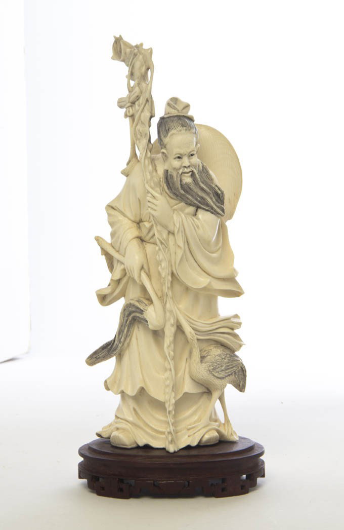 A Carved Ivory Figure, Height 9 inches.: A Carved Ivory Figure, depicting the figure with craggy staff and holding a ruyi scepter with a crane at his feet. Height 9 inches. Property from the Collection of Mr. and Mrs. Anthony Perino, Chicago
