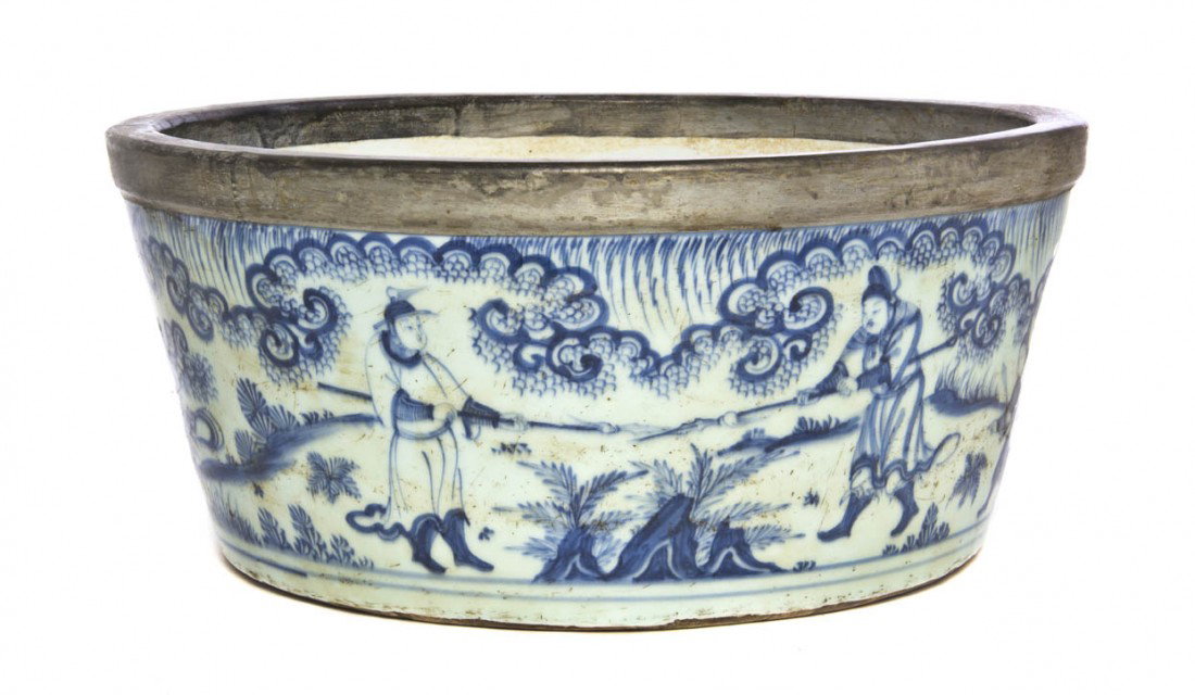 A Blue and White Basin, Diameter 15 1/8 inches.: A Blue and White Basin, depicting opposing warriors bearing spears in an outdoor setting beneath scrolling decoration, having a later metal rim over the lip. Diameter 15 1/8 inches.