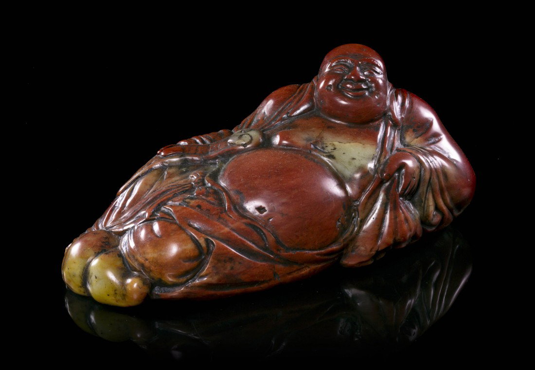 A Carved Steatite Figural Seal, Length 7 inches.: A Carved Steatite Figural Seal, of veined red colored stone, depicting the figure in a recumbent pose, holding a ruyi scepter and having a double gourd bottle at his feet, the flat underside having ca