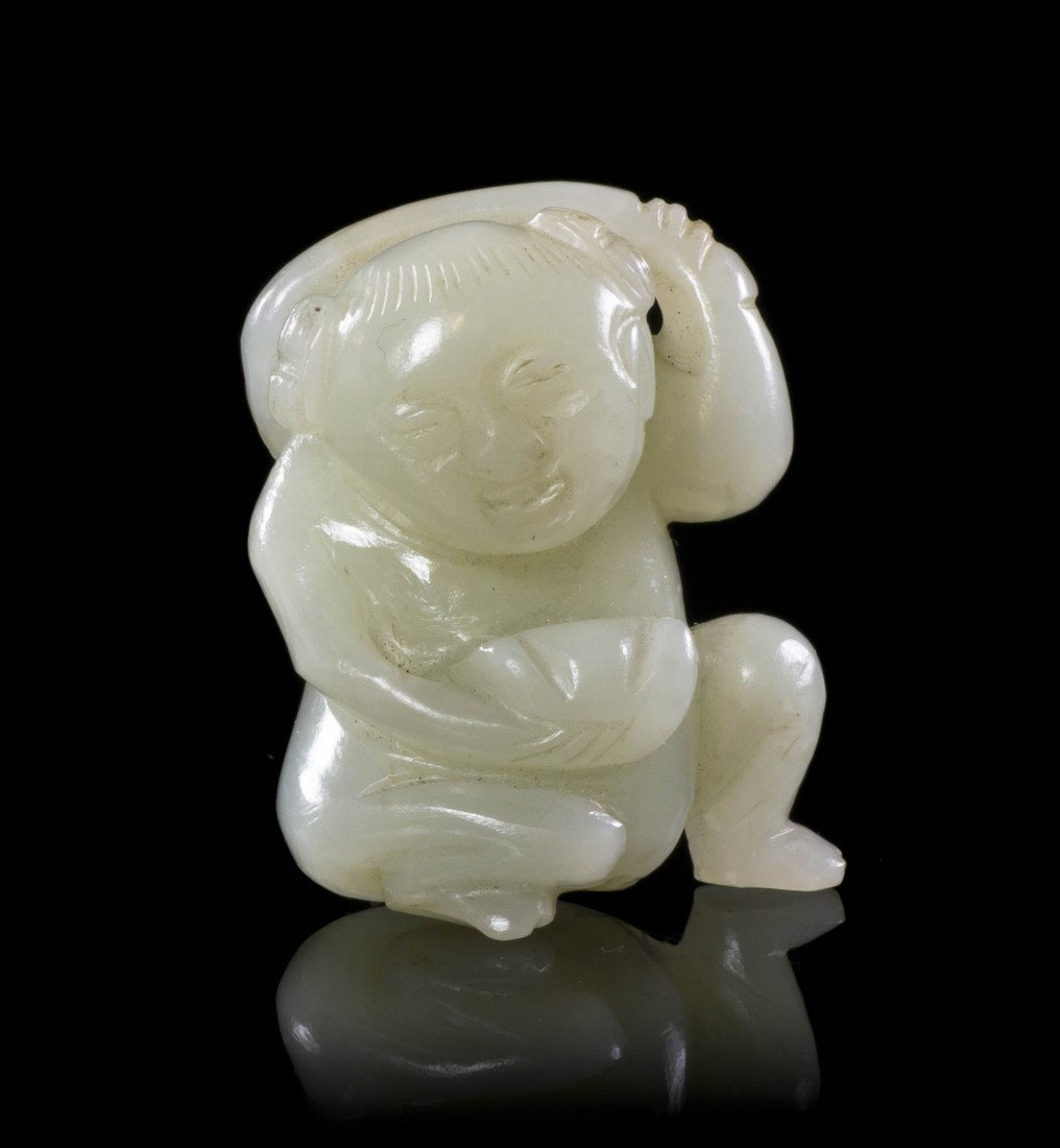 A Small Jade Carving of a Boy, Height 1 1/2 inches: A Small Jade Carving of a Boy, of near white stone, depicting the child in a seated pose with a bowl in one hand and the other slung over his shoulder. Height 1 1/2 inches. Property from the Estate of