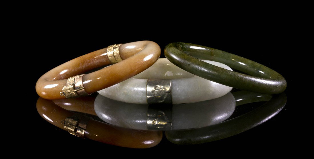 A Group of Three Jade Bangles, Diameter of largest: A Group of Three Jade Bangles, of white, green and russet colored stone, two with gold mounts. Diameter of largest 3 1/4 inches.
