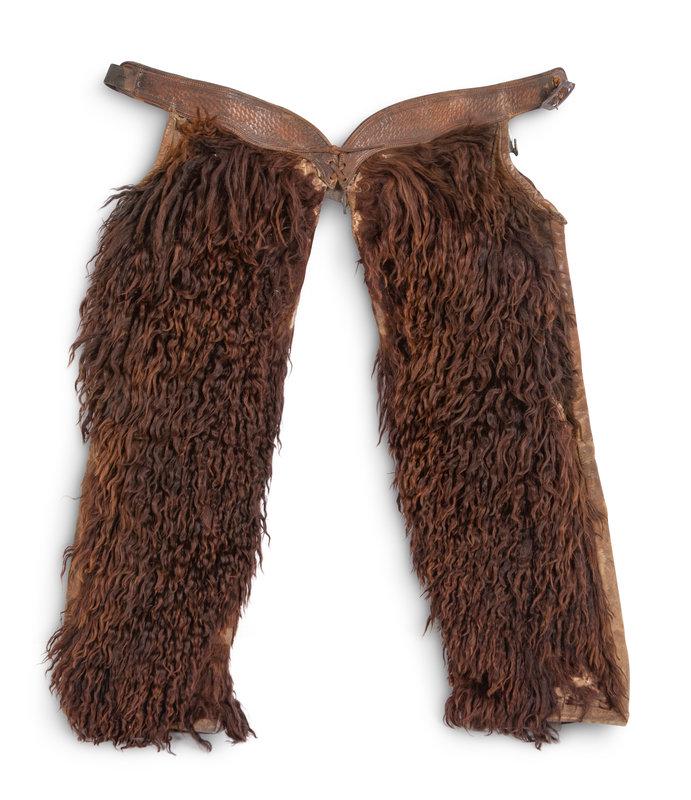A Pair of Buffalo Hide Wooley Chaps: A Pair of Buffalo Hide Wooley Chaps includes a metal wall hanging mount. Height 26 x width 24 inches. This lot is located in Denver. Property from the Estate of William