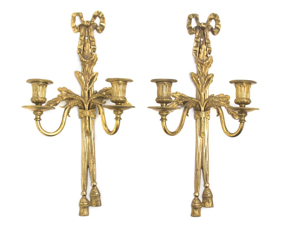 A Pair of Louis XVI Style Gilt Bronze Two-Light Sc: A Pair of Louis XVI Style Gilt Bronze Two-Light Sconces, each having ribbon-tied leaf and tassel back plate issuing the scrolling candle arms impressed HC. Height 15 1/4 inches.