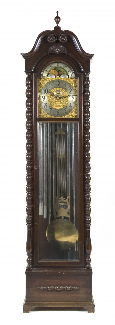 A Victorian Style Mahogany Tall Case Clock, Hersch: A Victorian Style Mahogany Tall Case Clock, Herschede Clock Co., having an arched pediment over the brass dial with moon phase, Arabic hours and secondary dial, the glazed case flanked by turned colum