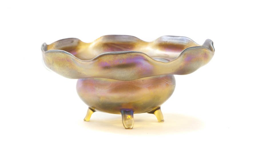 A Tiffany Studios Favrile Glass Footed Bowl, Diam: A Tiffany Studios Favrile Glass Footed Bowl, having a ruffled rim, raised on four feet, signed L.C.T. Y 5822. Diameter 7 5/8 inches. Property from the Lucie Sable Sandler Trust, Lincolnwood, Illinois