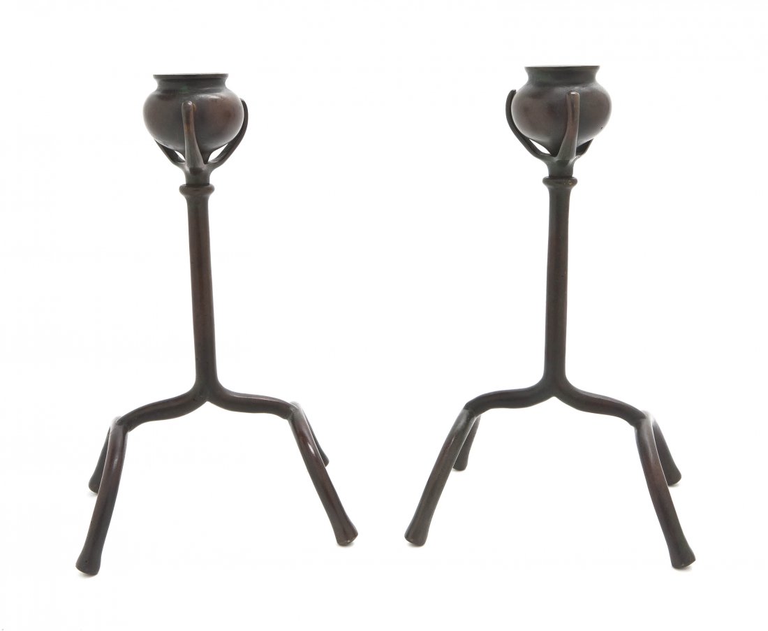 A Pair of Tiffany Studios Bronze Candlesticks, He: A Pair of Tiffany Studios Bronze Candlesticks, each having urn form candle cup, raised on a stick standard over four legs stamped Tiffany Studios New York. Height 9 1/2 inches.