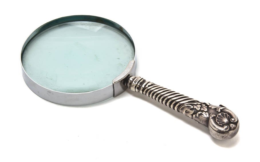 An English Silver Mounted Magnifying Glass, Danie: An English Silver Mounted Magnifying Glass, Daniel Holy & Co., Sheffield, 1830, the circular glass set with a twist and shell decorated handle. Length 7 3/8 inches. Property from O'Hara's Gallery, Chi