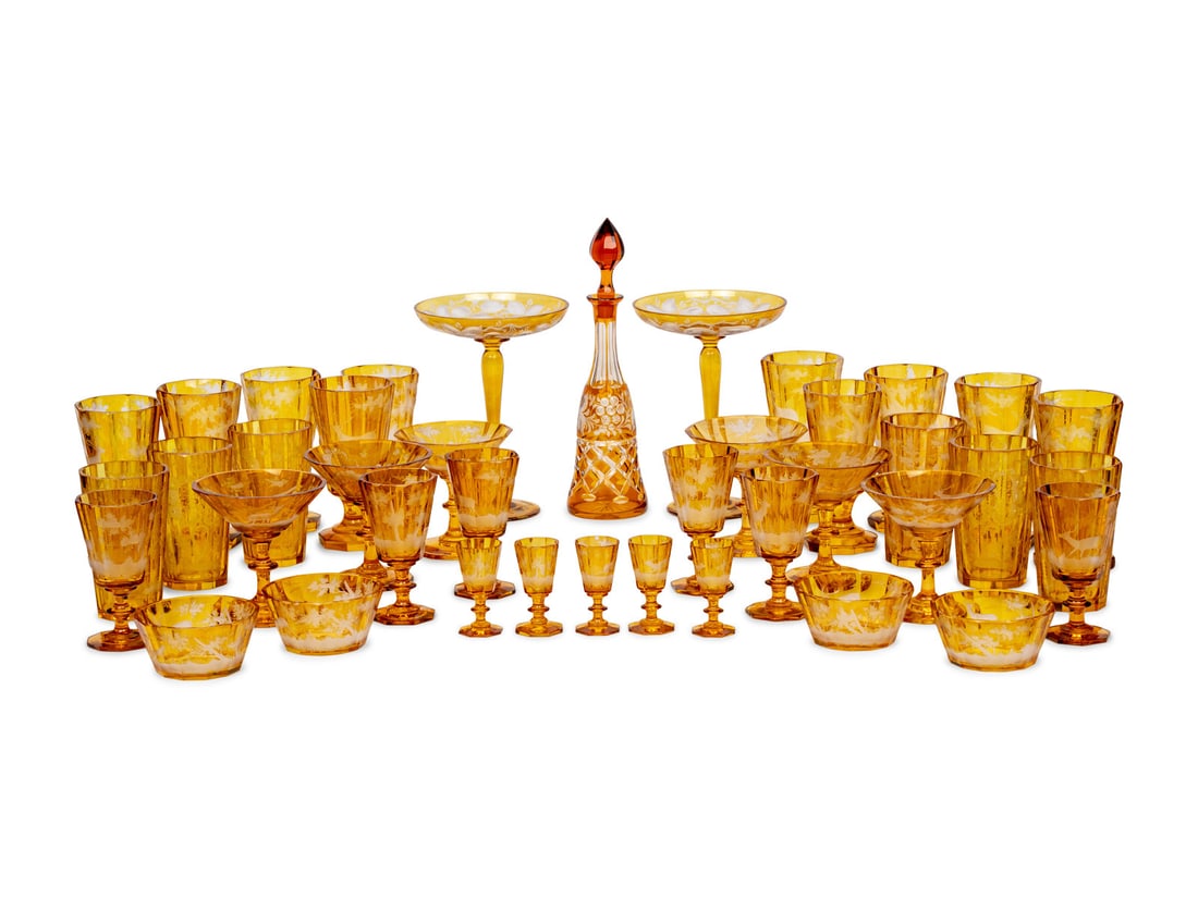 A Bohemian Amber Etched Glass Table Service: A Bohemian Amber Etched Glass Table Service 19th/20th Century comprising: 12 highball glasses 11 footed water goblets 11 wine stems 11 cordials 11 champagne coupes 12 fruit or sherbet bowls 12 dessert