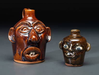 Two Southern Stoneware Face Jugs: Two Southern Stoneware Face Jugs 20th Century including one by Charlie Brown, Arden, North Carolina, dated 1990, and one by Matthew Hewell, Gillsville, Georgia. Height of larger 7 5/8 inches. This lot