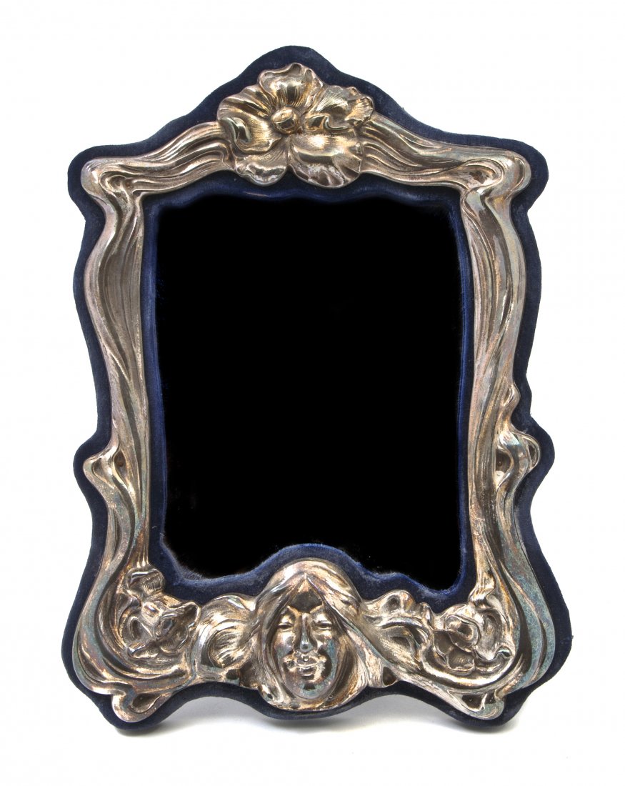 An American Art Nouveau Sterling Silver Table Mir: An American Art Nouveau Sterling Silver Table Mirror, the shaped plate set in a conforming frame cast with a flower and a female mask. Height 11 5/8 x width 8 5/8 inches.