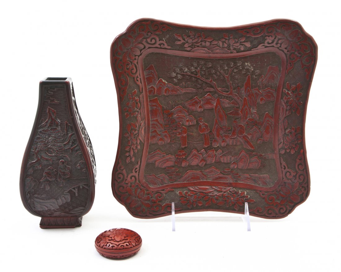 A Group of Three Cinnabar Lacquer Articles, Width: A Group of Three Cinnabar Lacquer Articles, comprising a square tray with rounded corners having central decoration depicting figures in a garden surrounded by a border of scrolling lotus blossoms, a