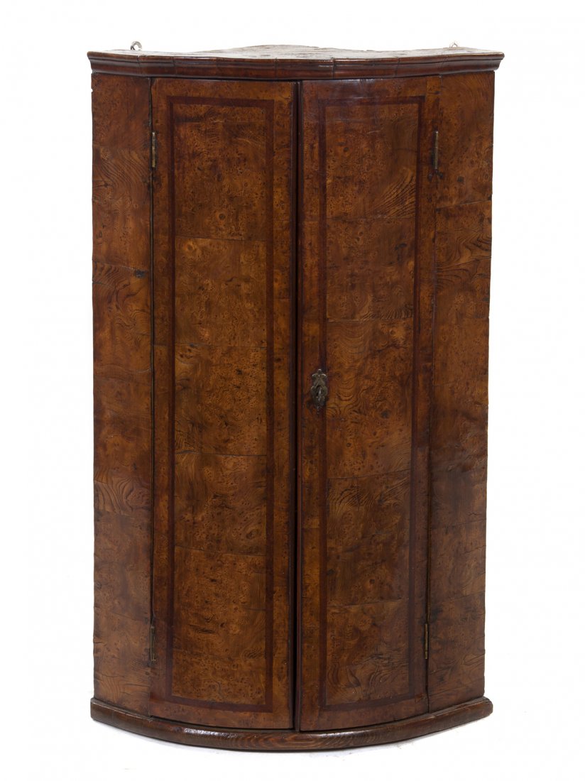 An English Burl Elm Corner Cabinet, Height 38 1/2 x: An English Burl Elm Corner Cabinet, of quarter round form, having two doors opening to three shelves. Height 38 1/2 x width 16 1/4 x depth 16 1/2 inches.