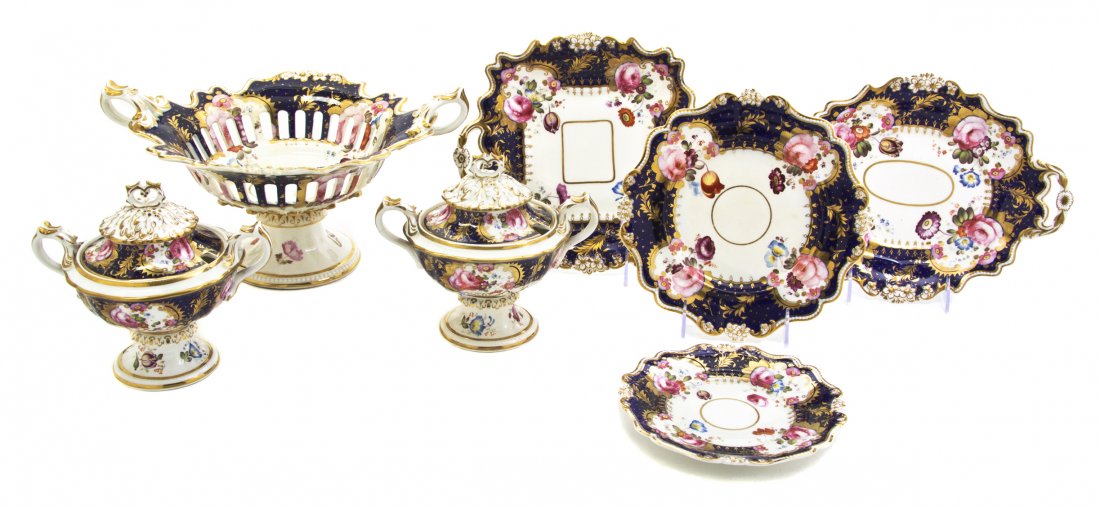 A Set of English Porcelain Table Articles, Width o: A Set of English Porcelain Table Articles, comprising a handled and pierced compote, 2 covered sauce tureens, 3 oval trays, 4 square trays and 17 plates. Width of compote over handles 14 1/8 inches.
