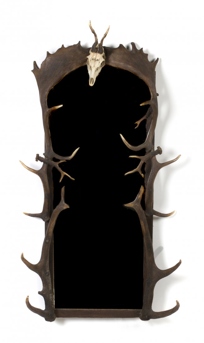 A Game Antler Mounted Mirror, Height 54 x width 27: A Game Antler Mounted Mirror, having various antlers including moose, elk and deer, surmounted by an Austrian trophy skull, set with a vertical arched beveled plate. Height 54 x width 27 3/4 inches.