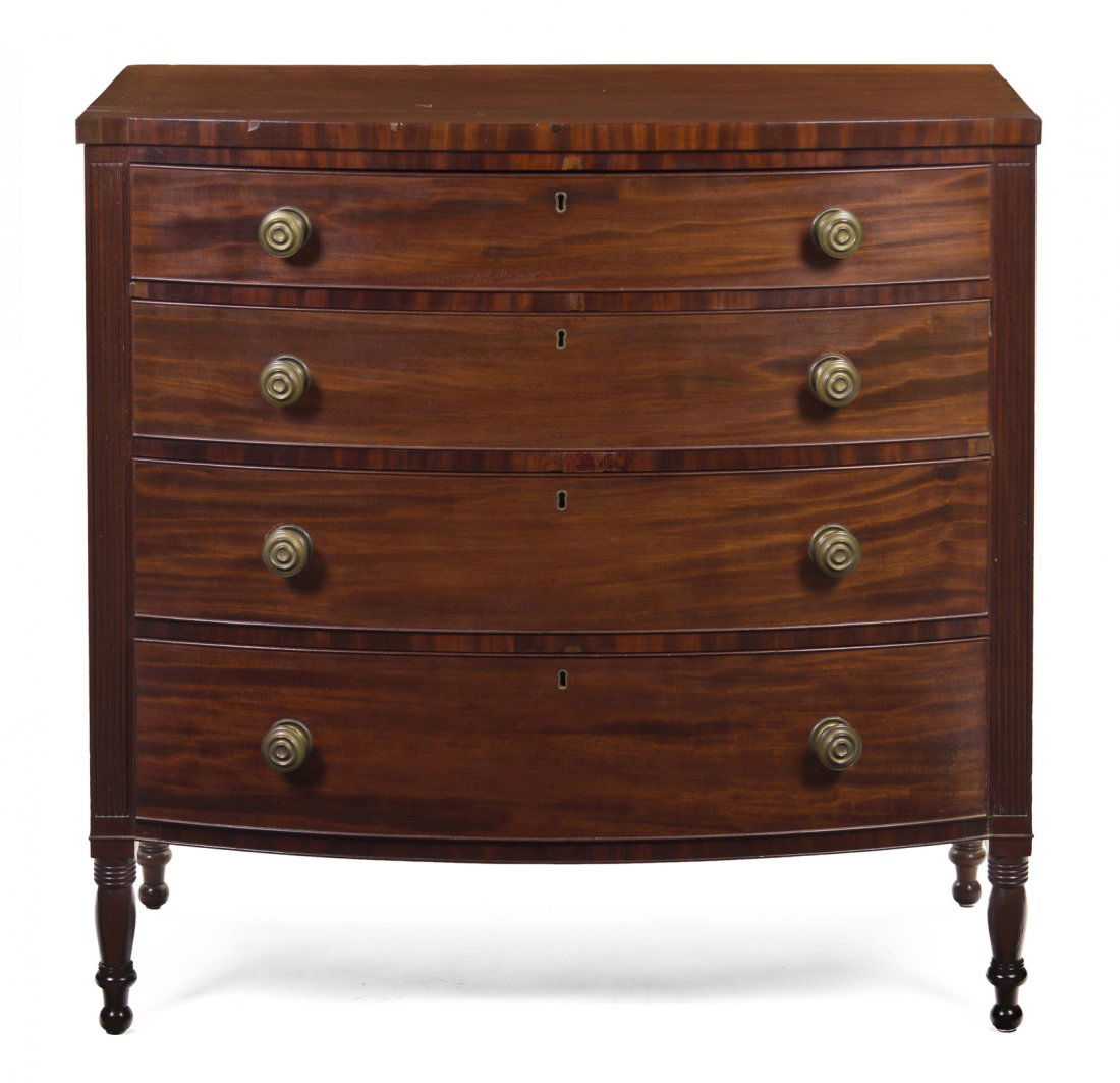 An American Sheraton Style Mahogany Chest of Drawe: An American Sheraton Style Mahogany Chest of Drawers, having a rectangular top with a bowed front over graduated drawers, raised on turned legs. Height 40 1/4 x width 41 1/2 x depth 23 inches. Propert
