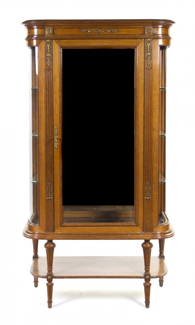 A Louis XVI Style Oak and Gilt Metal Mounted Vitri: A Louis XVI Style Oak and Gilt Metal Mounted Vitrine Cabinet, having a projecting molded cornice over a glass door and glass sides opening to a mirrored interior, raised on tapering fluted legs joined