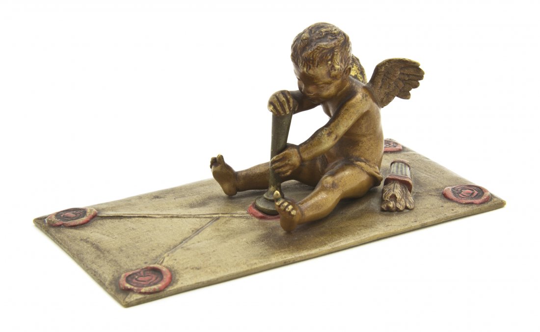 An Austrian Bronze Paperweight, Width 4 5/8 inche: An Austrian Bronze Paperweight, depicting Cupid seated and stamping his seal, with his quiver behind him, bearing the Bergman Foundry stamp to the underside. Width 4 5/8 inches.