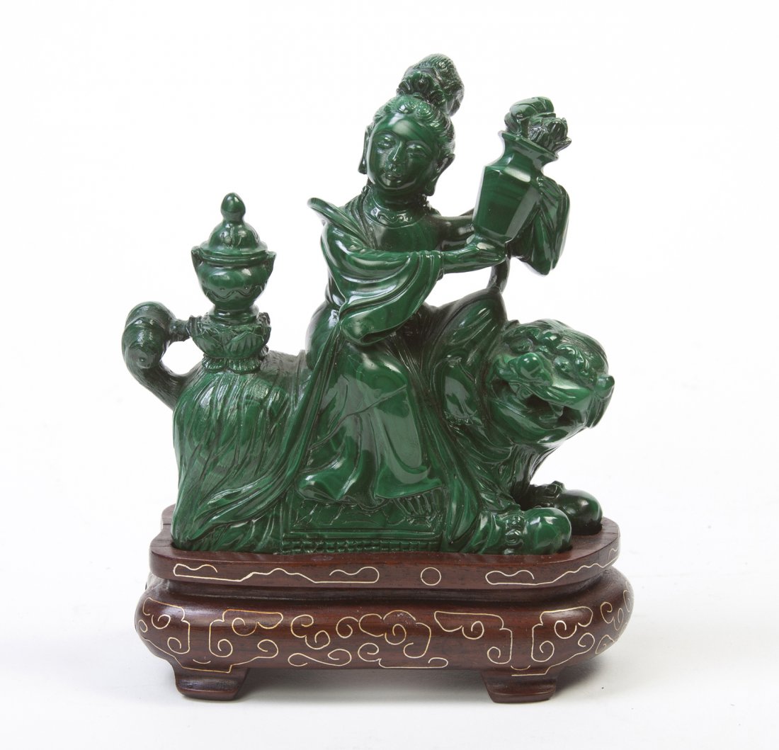 A Chinese Malachite Figural Carving, Height of fi: A Chinese Malachite Figural Carving, depicting a lady bearing a vase of flowers and riding a lion, raised upon a wire inlaid hardwood base. Height of figure 3 5/8 inches. Property of a Private Collect