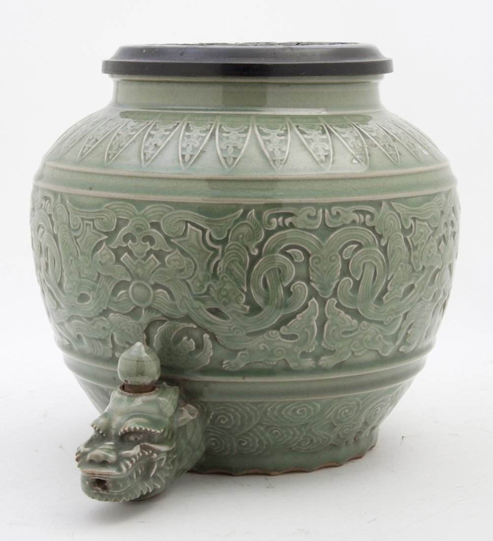 A Chinese Celadon Glazed Vessel, Height 10 3/4 in: A Chinese Celadon Glazed Vessel, the globular vessel decorated with scrolls, clouds and a dragon form spout, having a pierced carved lid and base. Height 10 3/4 inches. Property from the Estate of Hel