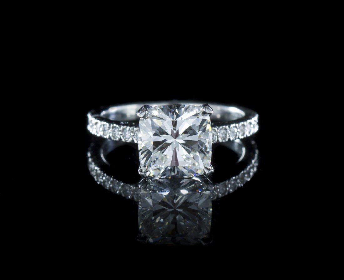 A Platinum and Cushion Cut Diamond Ring, Tiffany &: A Platinum and Cushion Cut Diamond Ring, Tiffany & Co., in the Novo style, consisting of a cushion shape brilliant cut diamond weighing approximately 2.43 carats and 16 round brilliant cut diamonds we