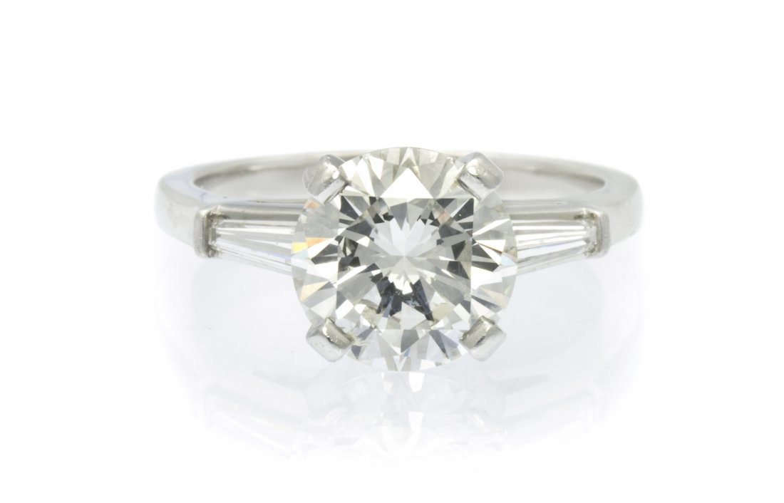 A Platinum and Diamond Ring, Cartier, 4.15 dwts.: A Platinum and Diamond Ring, Cartier, containing one round brilliant cut diamond weighing approximately 2.58 carats and two baguette cut diamonds weighing approximately 0.40 carat total. Accompanied b