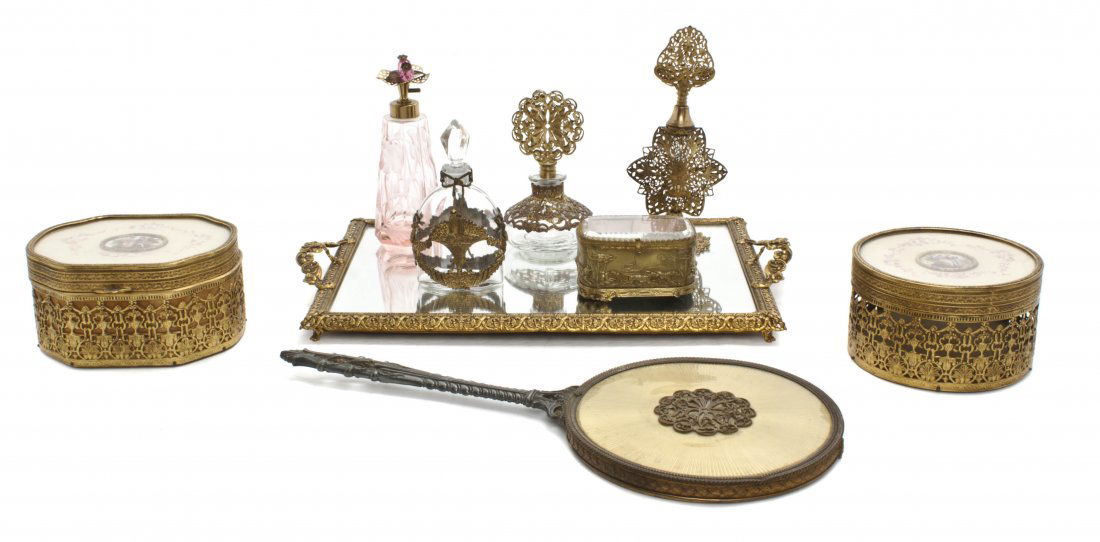 An Assembled Gilt Metal Mounted Dresser Set, Lengt: An Assembled Gilt Metal Mounted Dresser Set, comprising four perfume bottles, two circular boxes, a rectangular pin box, a hand mirror and a mirrored tray. Length of hand mirror 14 inches.