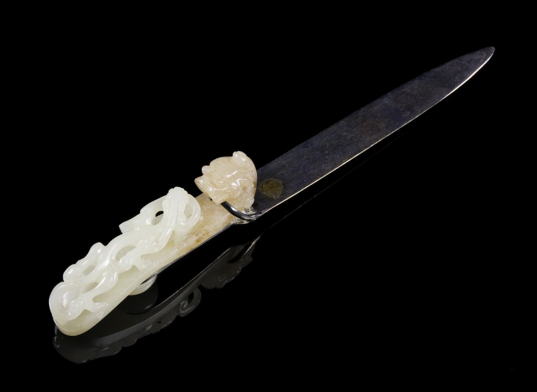 A Chinese White Jade Belthook, Length 3 3/8 inches: A Chinese White Jade Belthook, having a dragon head hook with a sinuous qilong on the top, mounted with silver as a letter opener. Length 3 3/8 inches. Property from the Estate of Mr. Charles Andrew S