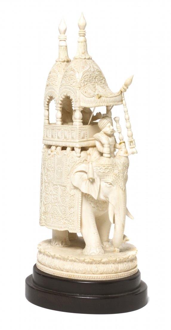 An Indian Carved Ivory Figural Group, Height of iv: An Indian Carved Ivory Figural Group, depicting figures riding in a houdah on the back of an elephant with a driver in front, the carriage and saddle cover with relief carved decoration, raised on a c