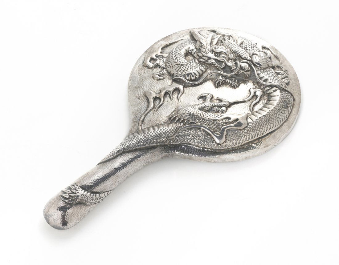 A Japanese Export Silver Hand Mirror, Length overa: A Japanese Export Silver Hand Mirror, of round, handled form, having a hand hammered finish and dragon decoration, bearing Japanese silver standard hallmark. Length overall 10 1/2 inches. Property of