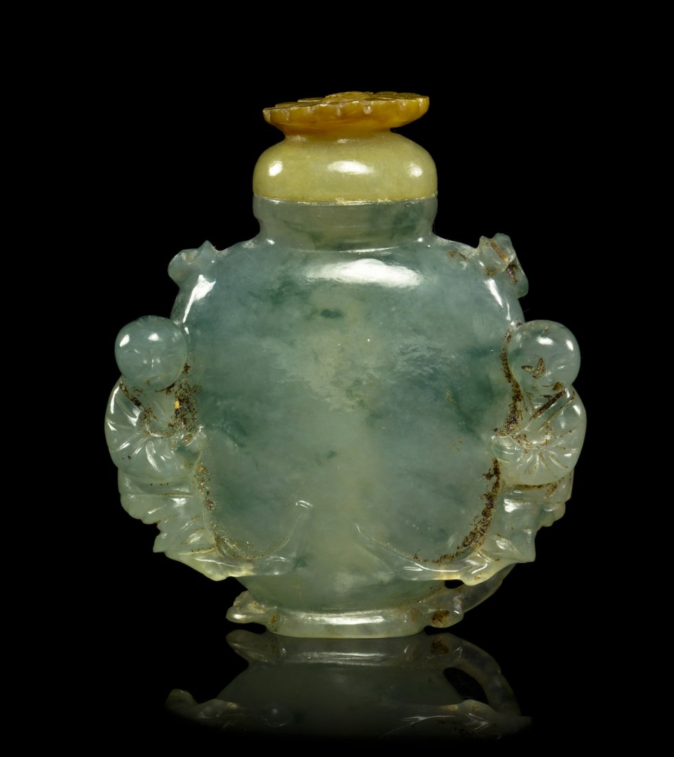 A Jadeite Snuff Bottle, Height of bottle 2 inches.: A Jadeite Snuff Bottle, of compressed flask form having raised carving on the sides of two boys, raised on an oval foot, having a carved hardstone floriform stopper. Height of bottle 2 inches. Propert