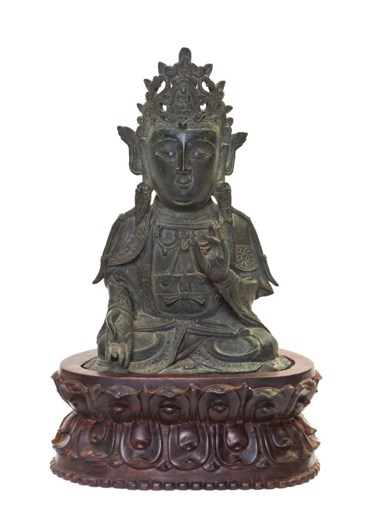 A Bronze Figure of a Buddhist Deity, Height of fig: A Bronze Figure of a Buddhist Deity, the figure wearing an openwork crown centered with a small Buddha figure and depicted in padmasana, raised on a lotus form carved wood base. Height of figure 7 7/8