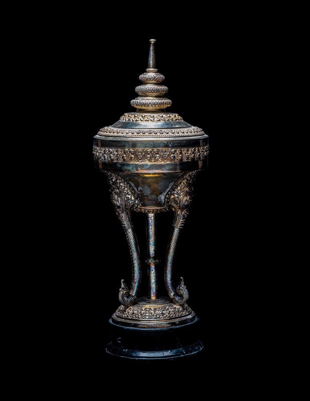 A Cambodian Silver Covered Vessel: A Cambodian Silver Covered Vessel 20th Century of chedi-form, raised on an ebonized wood base. Height 17 3/4 in., 45 cm. Size Height 17 3/4 in., 45 cm. Condi