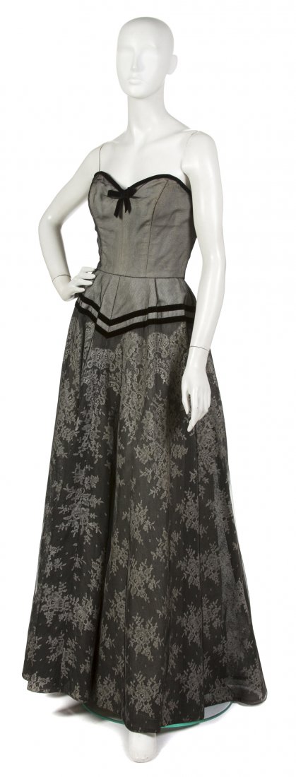A Hattie Carnegie Black Lace Ball Gown,: A Hattie Carnegie Black Lace Ball Gown, 1950s, velvet trim and bow at bust, sweetheart neckline, fitted waist, very flared skirt, fully lined. Labeled: Hattie Carnegie. Property from a New York City C