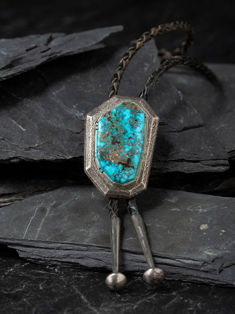 Larry Golsh (Pala Mission-Cherokee, b. 1942) Tufa Cast Silver and Morenci Turquoise Bolo Tie: Larry Golsh (Pala Mission-Cherokee, b. 1942) Tufa Cast Silver and Morenci Turquoise Bolo Tie marked LG with artist's chevron hallmark slide length 2 inches x width 1-1/2 inches, bolo length 30 inches,
