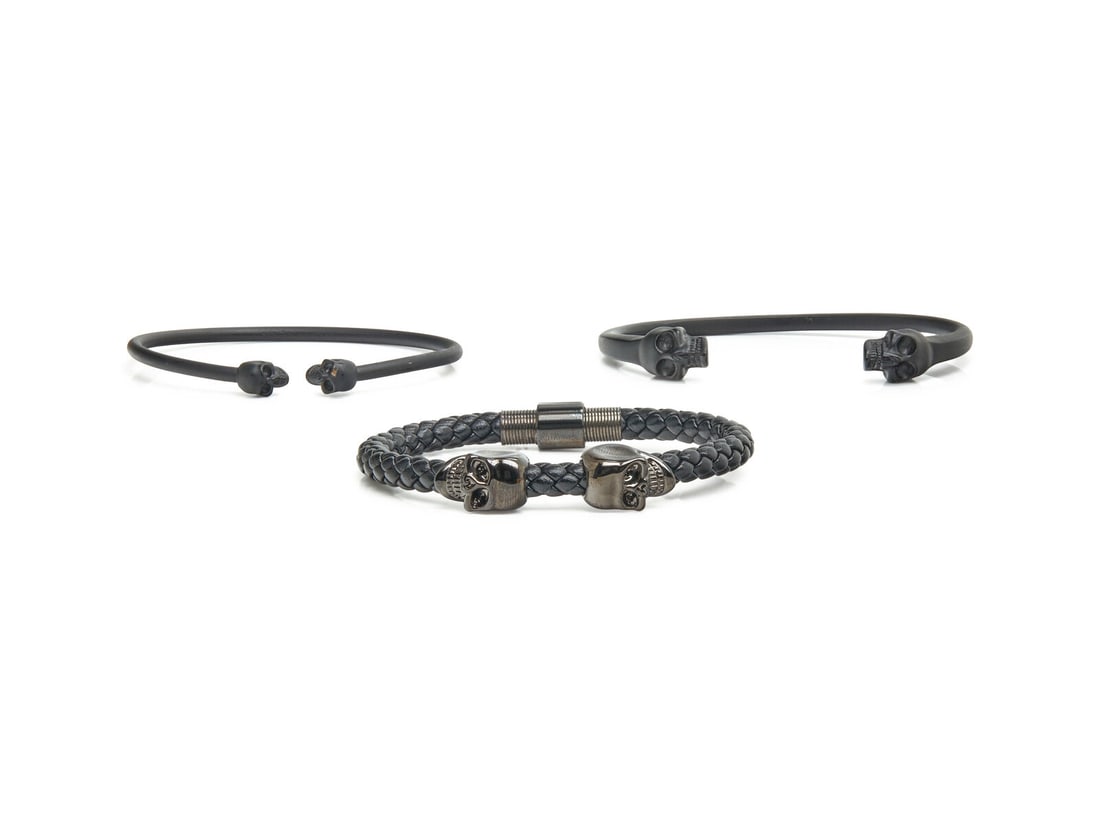 COLLECTION OF DESIGNER MEN'S BRACELETS: COLLECTION OF DESIGNER MEN'S BRACELETS Two blackened brass Alexander McQueen cuff bracelets with a braided leather and gunmetal black plated bracelet by Northskull. 7 1/2, 7, and 6 1/2 inches inner ci