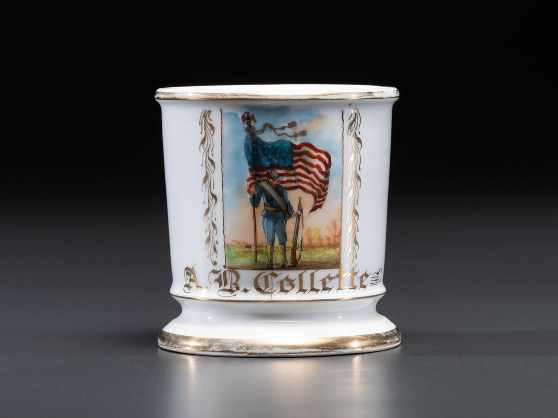 A Civil War Confederate Veteran's Porcelain Shaving Mug: A Civil War Confederate Veteran's Porcelain Shaving Mug Late 19th Century identified A.B. Collette and depicting a soldier in a field holding a rifle and flag. maker's mark to underside. Height 4 inch