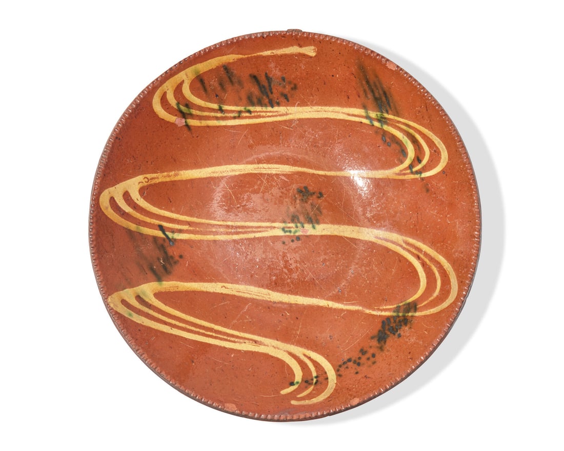 A Glazed and Slip-Decorated Redware Charger, Southeastern Pennsylvania, 19th Century: A Glazed and Slip-Decorated Redware Charger, Southeastern Pennsylvania, 19th Century Shallow form decorated with yellow slip and green splotches, coggled rim. Dia: 12 1/2 in. This lot is located in Ph