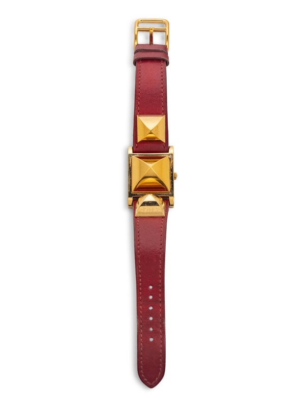 Hermès Médor Watch, 1994 : Hermès Médor Watch, 1994 "Médor" watch in crimson leather with gold-plated hardware. Concealed watch face under hinged central stud. Label: Hermès Serial No.: 695