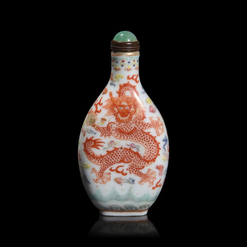 A Chinese Famille Rose Porcelain "Dragons" Snuff Bottle: A Chinese Famille Rose Porcelain "Dragons" Snuff Bottle Of flattened flask form, decorated with two sinuous dragons, one iron red and one green, among colorful clouds and flames, jadeite button to the
