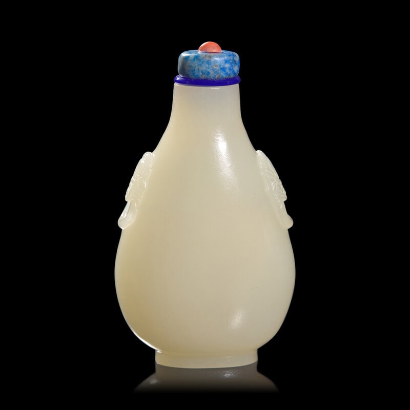 A Chinese Carved White and Russet Jade Snuff Bottle : A Chinese Carved White and Russet Jade Snuff Bottle Of flattened flask form, beast head "handles" at the shoulder, traces of russet skin to one side, lapis or sodalite button to stopper with coral fi