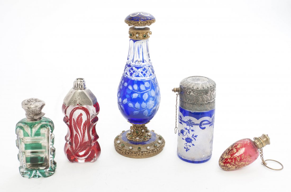 A Collection of Five Continental Scent Bottles, He: A Collection of Five Continental Scent Bottles, comprising a faux gem inset gilt metal mounted example in blue cut to clear with an enameled lid, a silvered metal mounted blue cut to an etched clear g