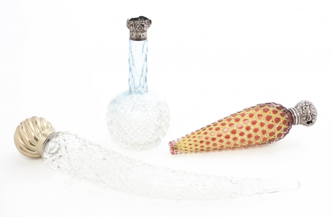 Three Cut Glass Perfume Bottles, Length of longest: Three Cut Glass Perfume Bottles, comprising a flattened tapering example with repeating hexagonal decoration cut in red to clear to yellow, a pale blue bulbous form example with an English silver moun