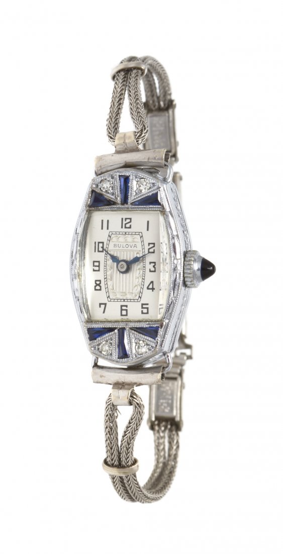 An Art Deco 14 Karat White Gold, Diamond and Synth: An Art Deco 14 Karat White Gold, Diamond and Synthetic Sapphire Watch, Bulova, 24.75 X 15.00 mm case dimensions, silvered dial with engraved central section, black Arabic numerals, blued steel index h
