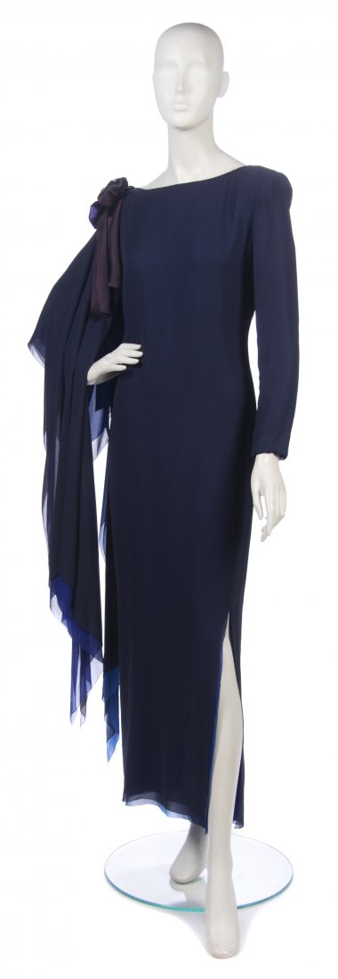 A Navy Chiffon Evening Dress,: A Navy Chiffon Evening Dress, attributed to Pierre Cardin, varying shades of layered blue chiffon, asymmetrical draped sleeve with bow detail to one shoulder. Property from the Estate of the Marquise 