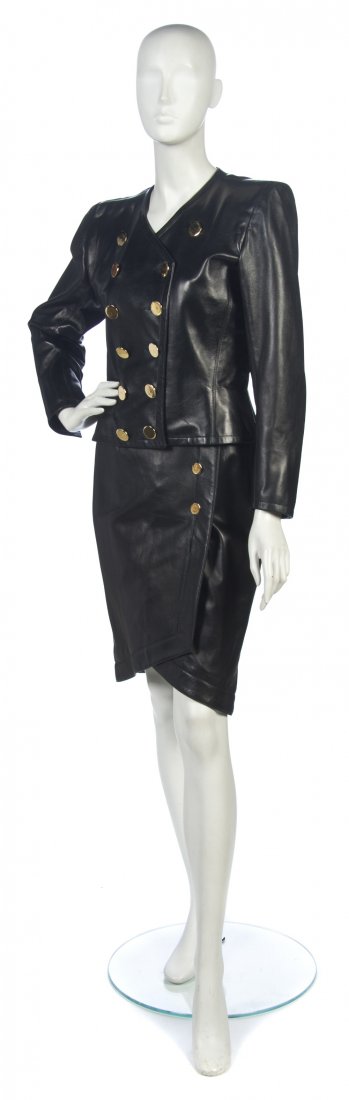 An Yves Saint Laurent Black Leather Two Piece Suit: An Yves Saint Laurent Black Leather Two Piece Suit, comprised of a skirt and jacket, with gold buttons. Labeled: Saint Laurent. Size 40.